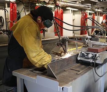 学生穿着防护焊具在工作台上焊接